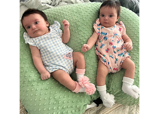 Twin girls Delaney and Bexley are laying next to each other