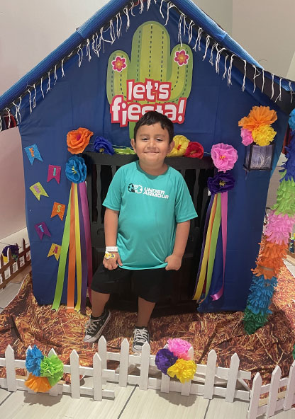 Lukas Ramos stands in front of a playhouse at CHRISTUS Children's
