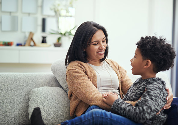 A mom and her young son sit on the couch and talk