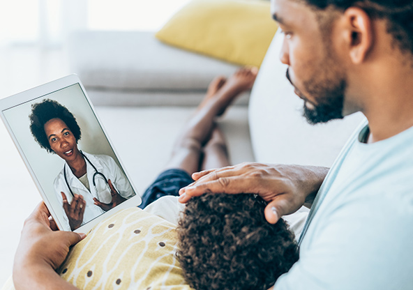 Dad with child talking to clinician through telemedicine